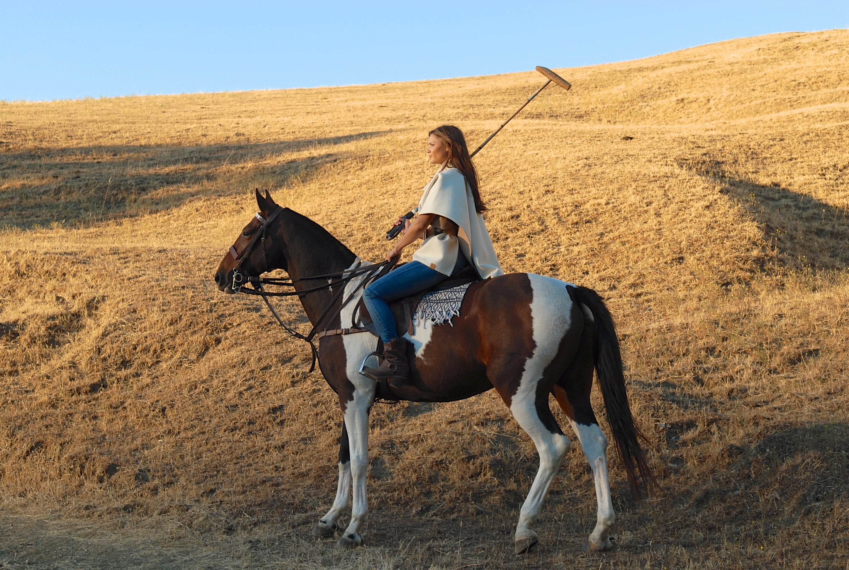 Model on polo horse wearing white Stick and Ball poncho
