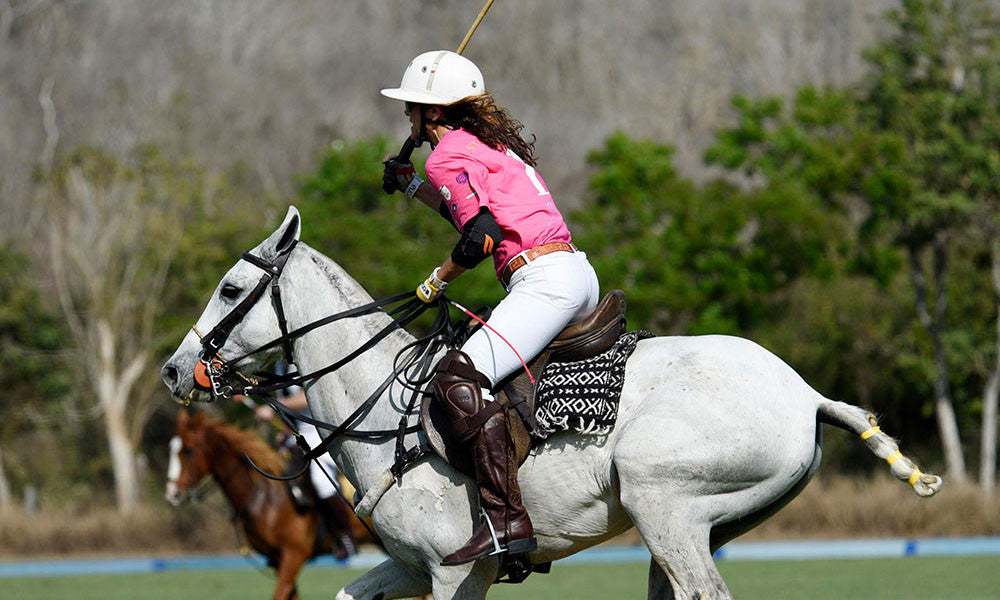Founder Elizabeth Welborn playing polo on a white horse