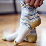 Woman putting on Pampa Boot Sock in Cream with cream & gold - Stick & Ball 