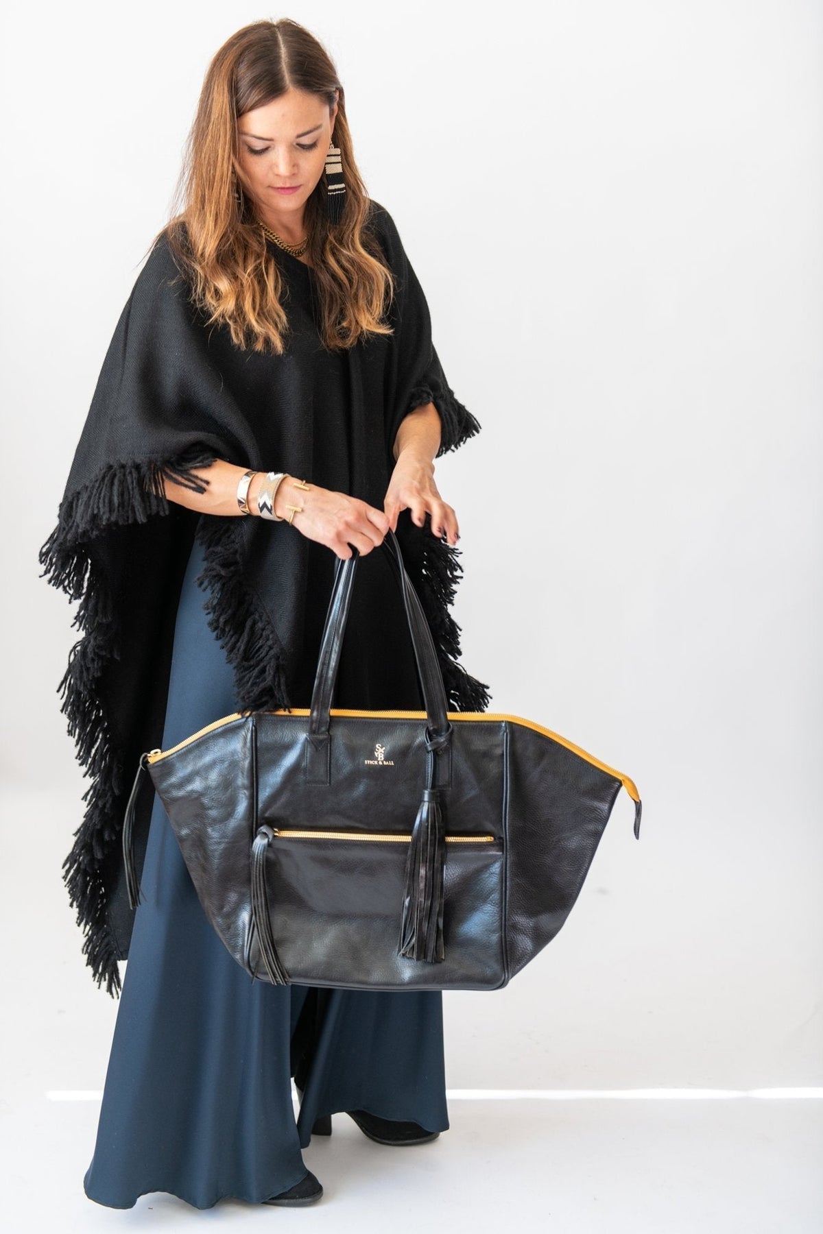 woman styled in Stick and Ball signature long fringed alpaca poncho with Palermo Soho leather tote
