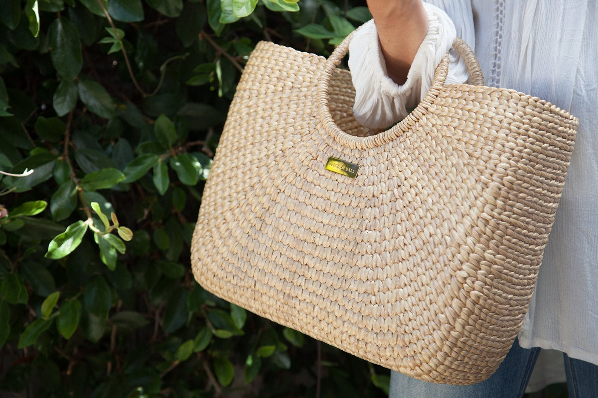 woman carrying Stick and Ball woven tote bag at summer outdoor event