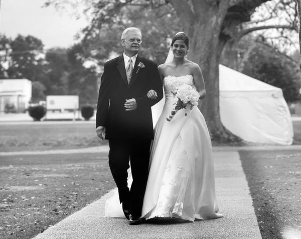Black & White Photo of Stick & Ball founder, Elizabeth, on her wedding day walking down the isle with her father.