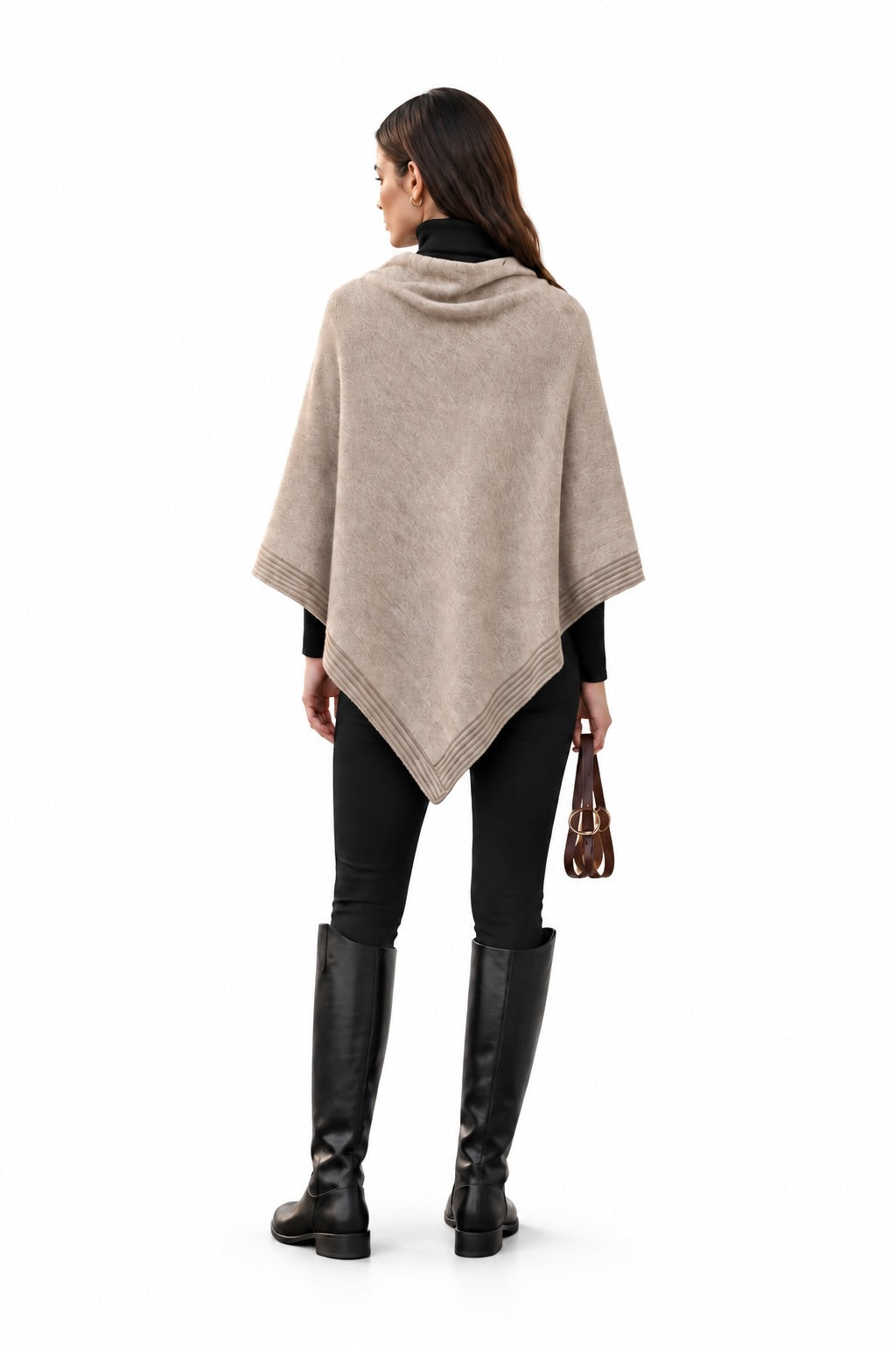 A woman shown from the back wearing a taupe triangular poncho over a black outfit, with black knee-high boots and holding equestrian reins, against a plain white background.